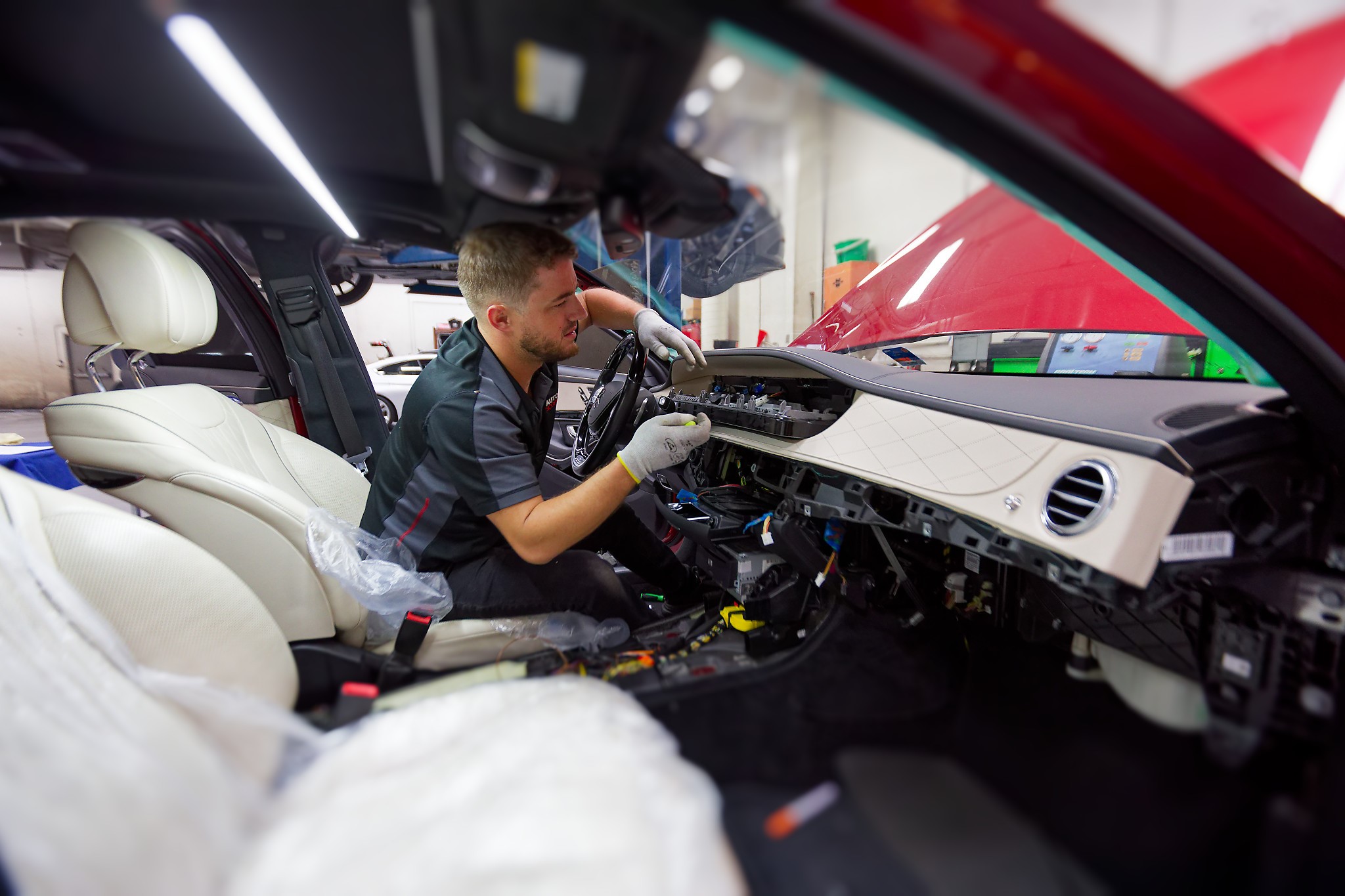 Autoscope technician working from the driver's seat of a Mercedes with the dashboard disassembled for instrument cluster replacement