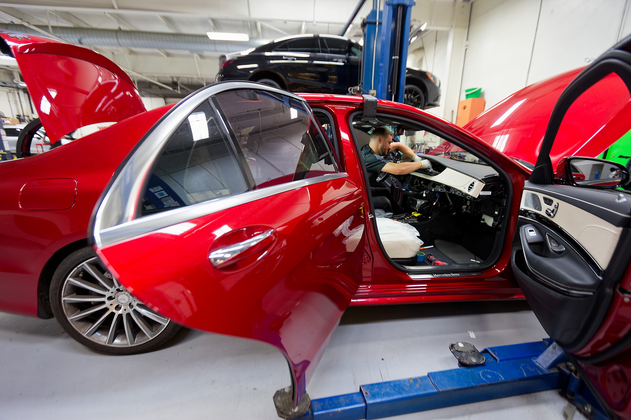 Red Mercedes sedan in the Autoscope service bay with doors open during digital instrument cluster replacement