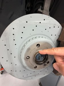 Technician pointing at the Min. TH minimum thickness marking on the rotor hat