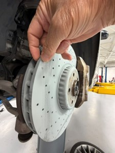 New Mercedes-AMG rotor held up beside the installed rotor for comparison