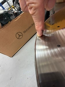 Edge of a new Mercedes-Benz OEM brake rotor beside its original packaging